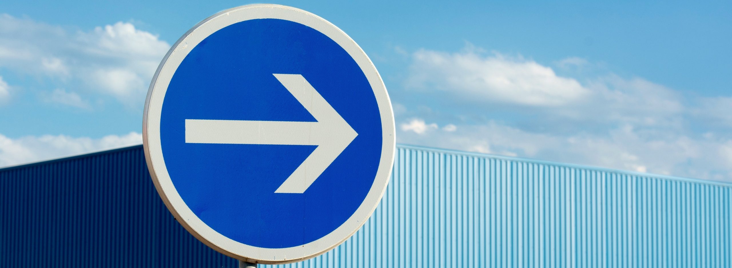 a blue sign with a white arrow pointing right