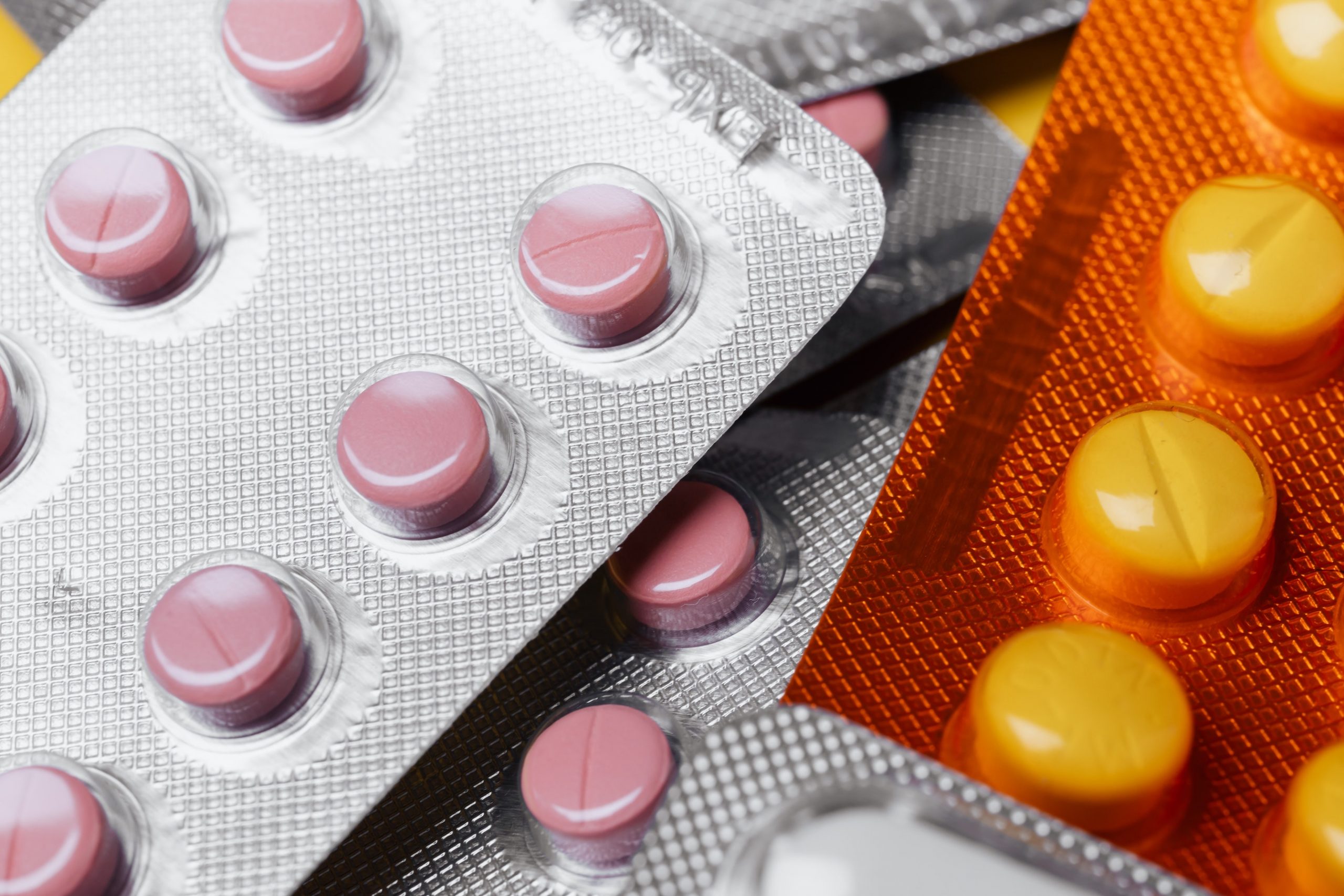 Several packets of medication including pink and yellow tablets